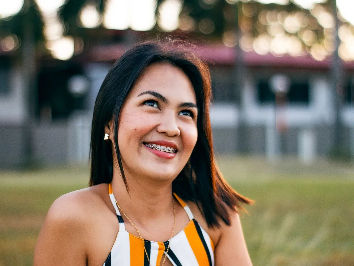 A young woman with braces smiling outdoors