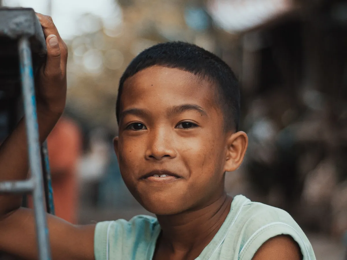 A young boy smiling at the camera outdoors